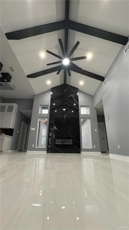 unfurnished living room with beamed ceiling and high vaulted ceiling