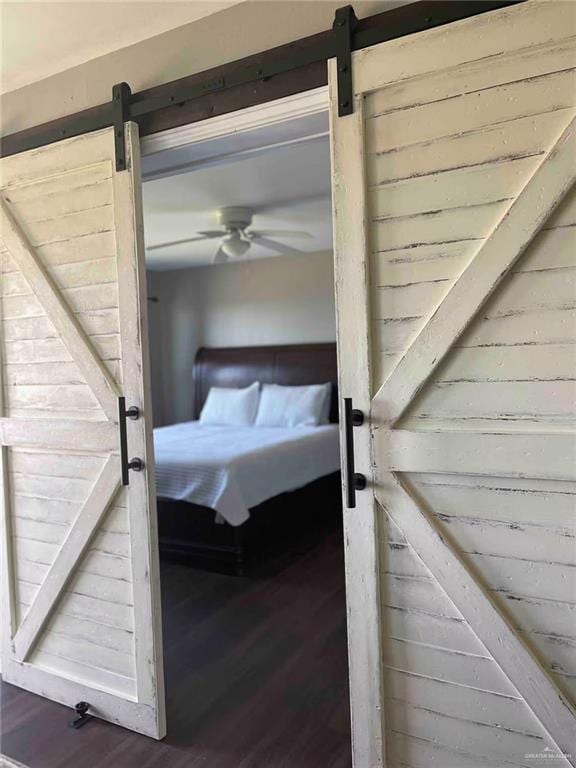 interior space featuring ceiling fan, wood-type flooring, and a barn door