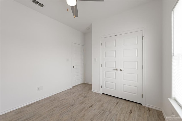 unfurnished bedroom with ceiling fan, light wood-type flooring, and a closet