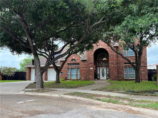 traditional-style house featuring brick siding, fence, driveway, and a garage