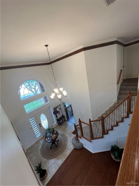 entrance foyer with stairway, wood finished floors, a towering ceiling, baseboards, and a notable chandelier