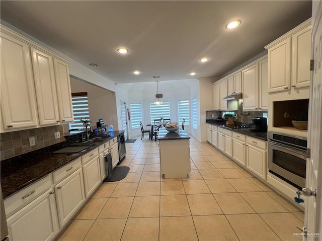 kitchen with tasteful backsplash, a sink, stainless steel oven, under cabinet range hood, and recessed lighting