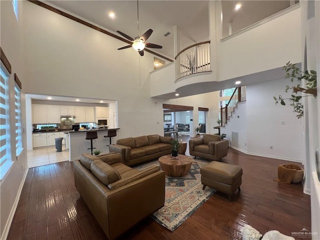 living area featuring light wood-style flooring, baseboards, ceiling fan, and a healthy amount of sunlight