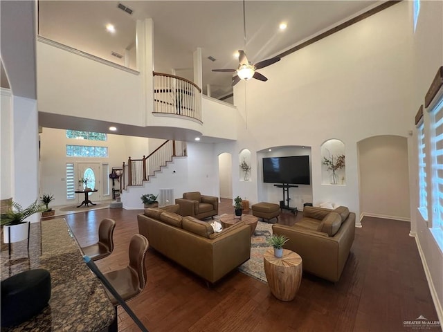 living area with arched walkways, visible vents, dark wood-type flooring, and stairs