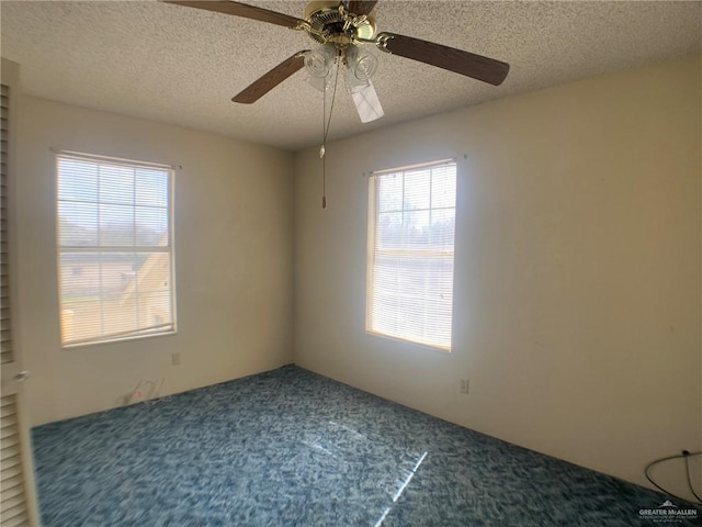 carpeted empty room featuring ceiling fan and a textured ceiling