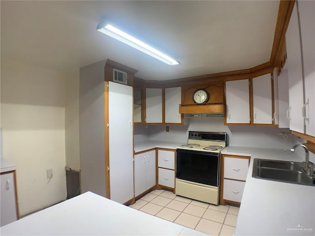 kitchen with range with electric cooktop, light tile patterned flooring, sink, and white cabinets