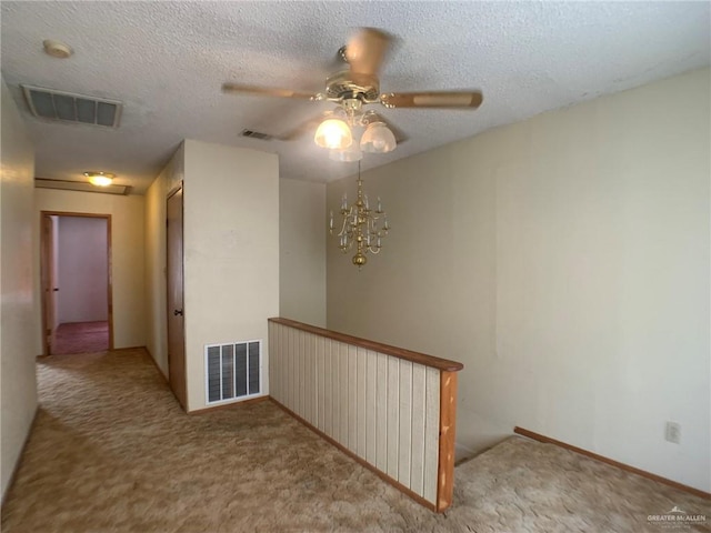 hall with light carpet, a notable chandelier, and a textured ceiling