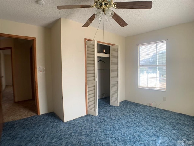 unfurnished bedroom featuring dark colored carpet, ceiling fan, a textured ceiling, and a closet