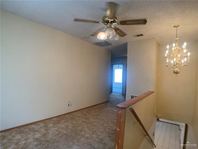 carpeted spare room featuring an inviting chandelier and a textured ceiling