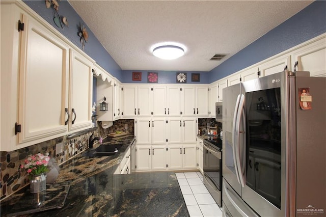 kitchen with appliances with stainless steel finishes, tasteful backsplash, dark stone counters, a textured ceiling, and white cabinets