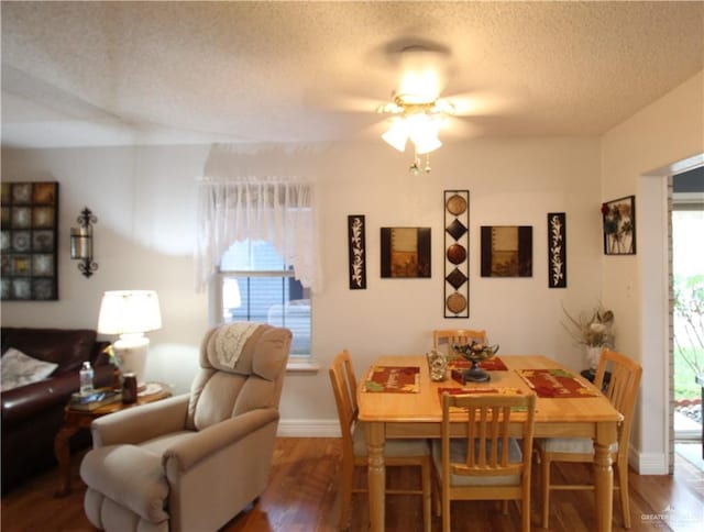 dining space with ceiling fan, wood-type flooring, and a textured ceiling