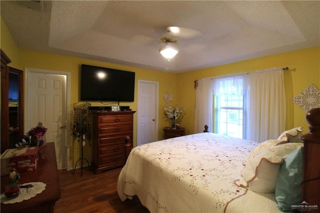 bedroom featuring ceiling fan, a tray ceiling, and dark hardwood / wood-style floors