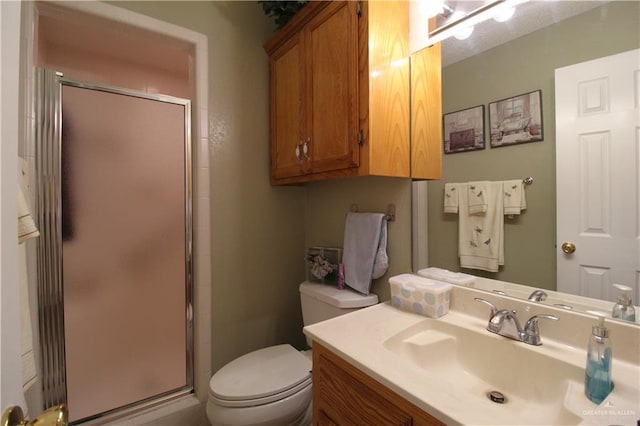 bathroom with a shower with shower door, vanity, and toilet