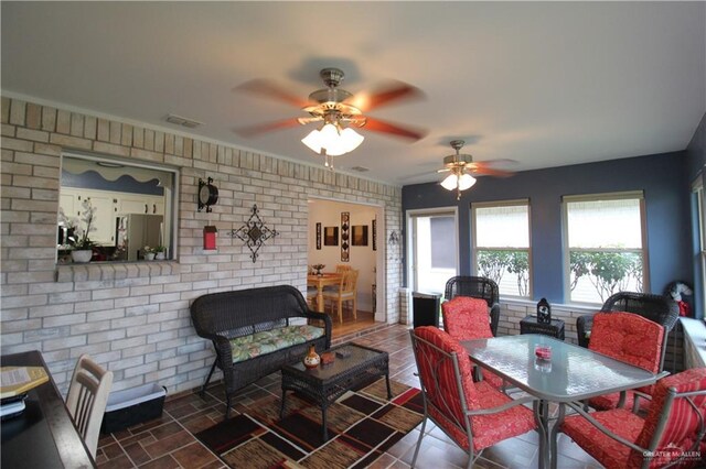 living room with ceiling fan and brick wall