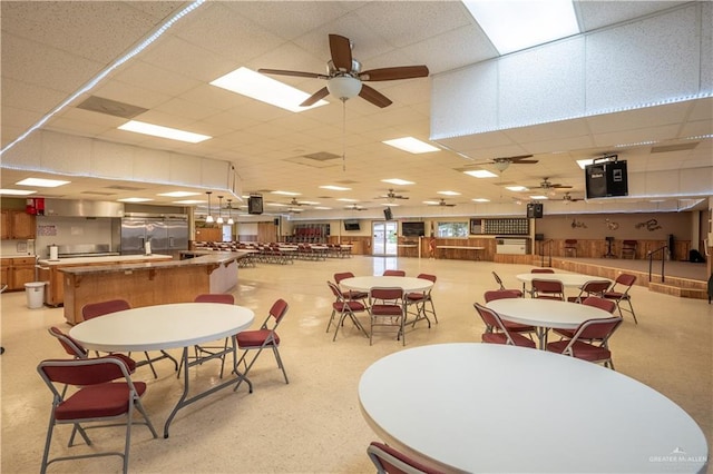 dining area featuring ceiling fan and a drop ceiling