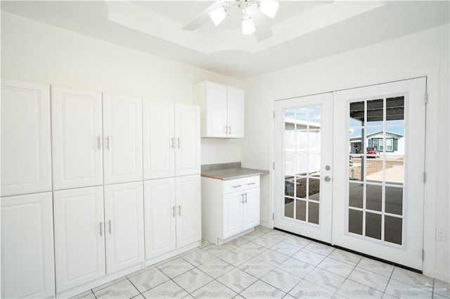 kitchen with white cabinets, ceiling fan, a raised ceiling, and french doors