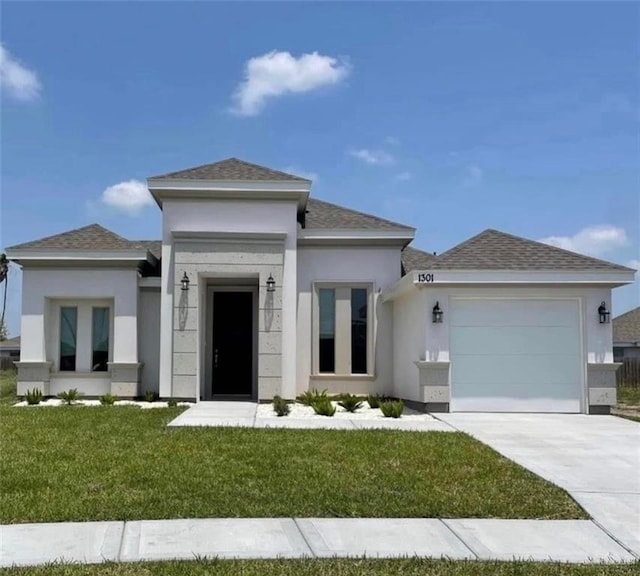 1301 Frente Al Mar Dr, Weslaco, TX 78596 - prairie-style home featuring a garage, concrete driveway, a front yard, stucco siding, and roof with shingles