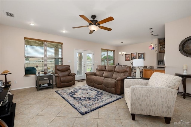 living room featuring ceiling fan with notable chandelier, light tile patterned floors, and french doors