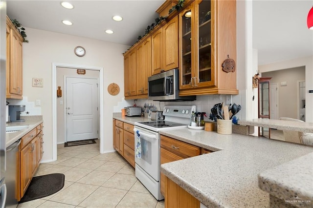 kitchen featuring light stone counters, light tile patterned floors, backsplash, and appliances with stainless steel finishes