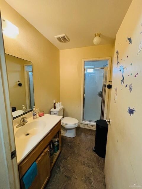 bathroom with vanity, toilet, and a shower with door