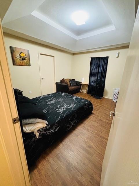 bedroom with hardwood / wood-style flooring and a raised ceiling