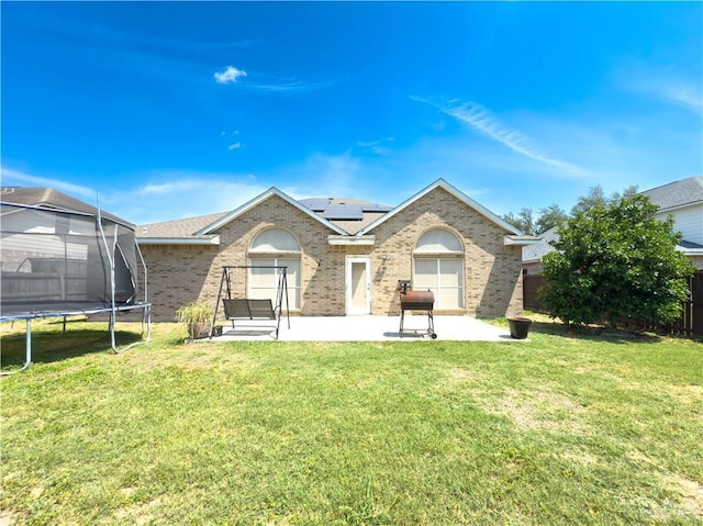 3004 San Federico Rd, Mission, TX 78572 - back of property with a patio area, a trampoline, roof mounted solar panels, a yard, and brick siding