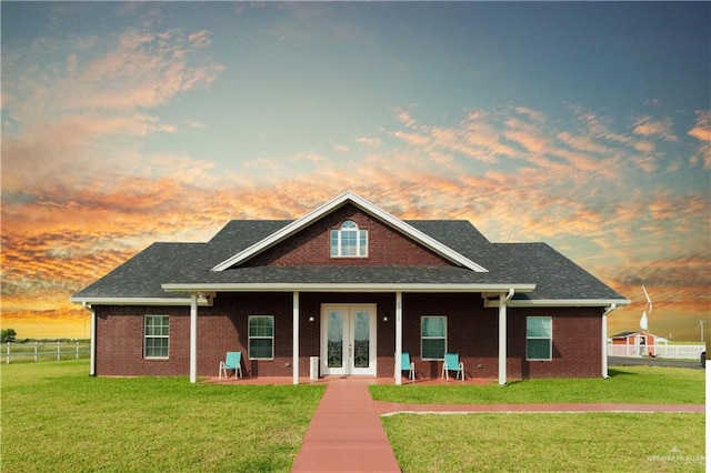 view of front of house with french doors and a lawn