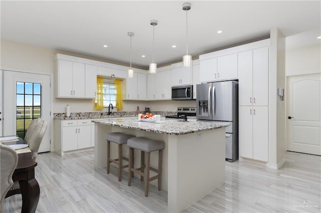 kitchen with hanging light fixtures, a center island, a breakfast bar area, white cabinets, and appliances with stainless steel finishes