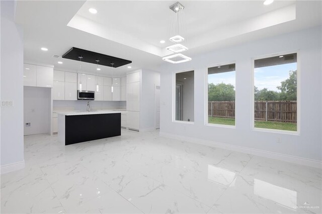 1232 Bridle Way, San Benito, TX 78586 - kitchen with stainless steel microwave, modern cabinets, a raised ceiling, baseboards, and white cabinetry