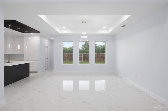 1232 Bridle Way, San Benito, TX 78586 - unfurnished living room featuring a raised ceiling, baseboards, recessed lighting, light marble finish floors, and a sink