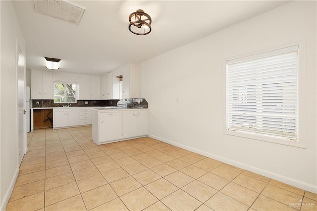 816 E 12th St, Mission, TX 78572 - kitchen featuring a peninsula, white cabinetry, light tile patterned floors, decorative backsplash, and freestanding refrigerator