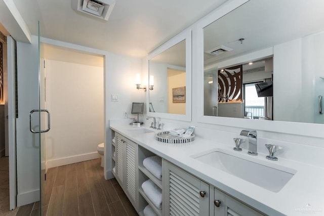 full bath with double vanity, a sink, wood finished floors, and toilet