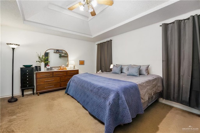 bedroom with carpet flooring, a tray ceiling, and ceiling fan