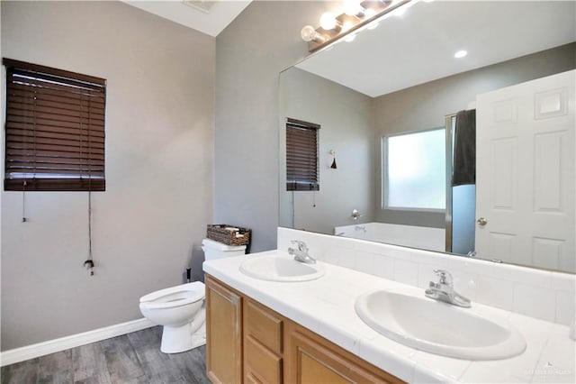 5302 Huisache Ave, Pharr, TX 78539 - bathroom featuring double vanity, toilet, wood finished floors, baseboards, and a bath