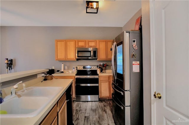 5302 Huisache Ave, Pharr, TX 78539 - kitchen with stainless steel appliances, a sink, wood finished floors, light countertops, and light brown cabinets