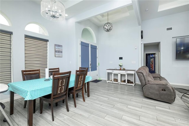 1102 Palm Blvd, Laguna Vista, TX 78578 - dining room featuring a chandelier, a towering ceiling, light wood-type flooring, baseboards, and a tray ceiling