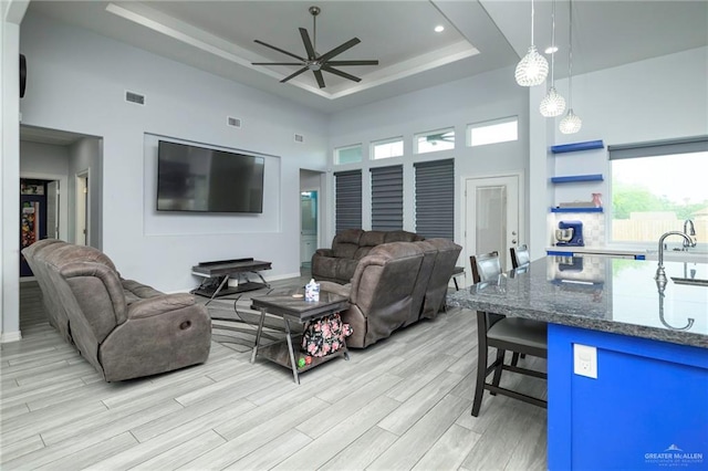 1102 Palm Blvd, Laguna Vista, TX 78578 - living room with a towering ceiling, a raised ceiling, a ceiling fan, light wood finished floors, and plenty of natural light