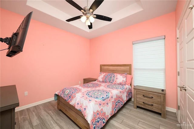 1102 Palm Blvd, Laguna Vista, TX 78578 - bedroom featuring a tray ceiling, wood finished floors, baseboards, and a ceiling fan