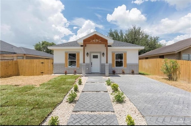bungalow-style home featuring stucco siding, fence private yard, brick siding, and a front yard