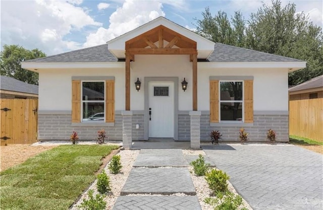 bungalow featuring fence, a shingled roof, and brick siding
