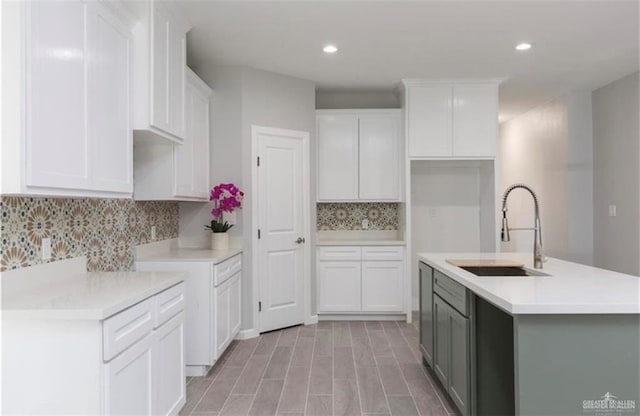 kitchen featuring recessed lighting, decorative backsplash, a sink, and an island with sink