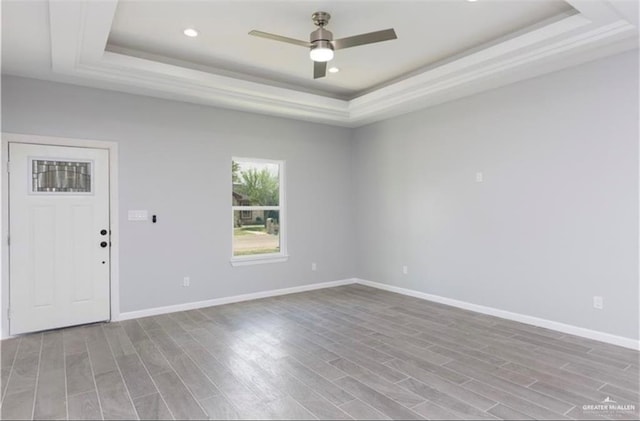interior space featuring ceiling fan, wood finished floors, baseboards, a tray ceiling, and recessed lighting