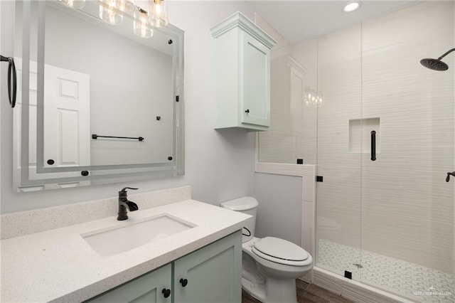 bathroom with hardwood / wood-style floors, vanity, an enclosed shower, and toilet