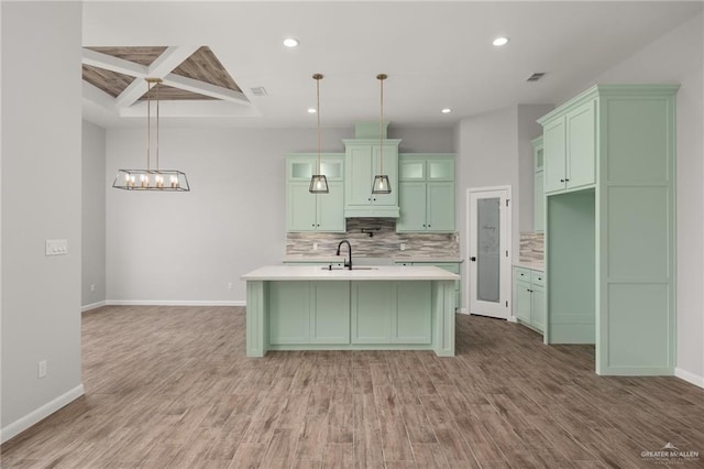 kitchen featuring decorative light fixtures, tasteful backsplash, light hardwood / wood-style floors, and an island with sink