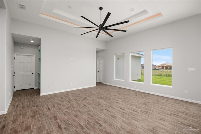 empty room featuring ceiling fan, a raised ceiling, and light hardwood / wood-style flooring