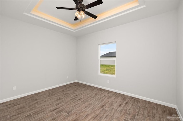 spare room with a tray ceiling, ceiling fan, and hardwood / wood-style flooring