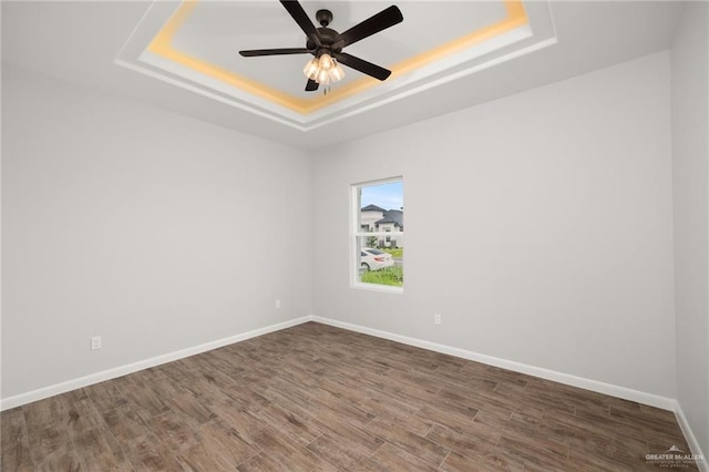 spare room featuring ceiling fan, a raised ceiling, and wood-type flooring