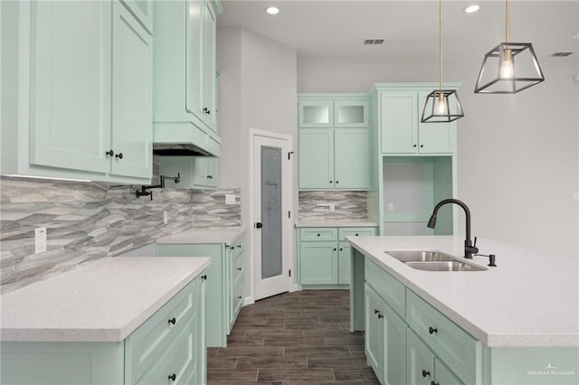 kitchen with a kitchen island with sink, sink, dark hardwood / wood-style floors, decorative backsplash, and decorative light fixtures