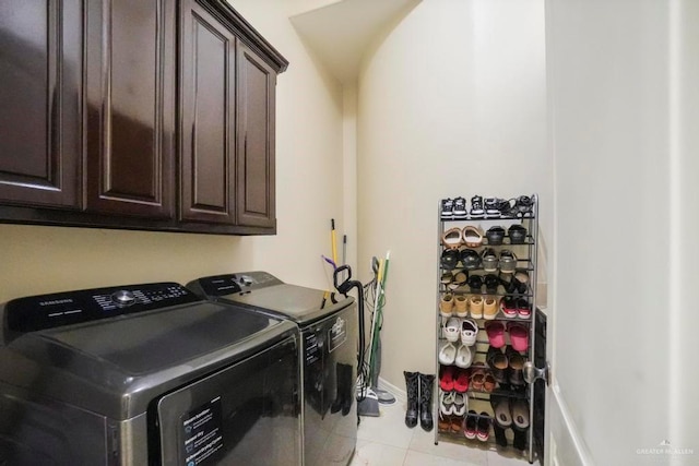 laundry area with cabinets, light tile patterned floors, and washing machine and clothes dryer