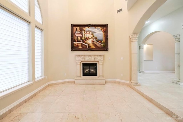 unfurnished living room featuring a healthy amount of sunlight, ornate columns, and a high ceiling